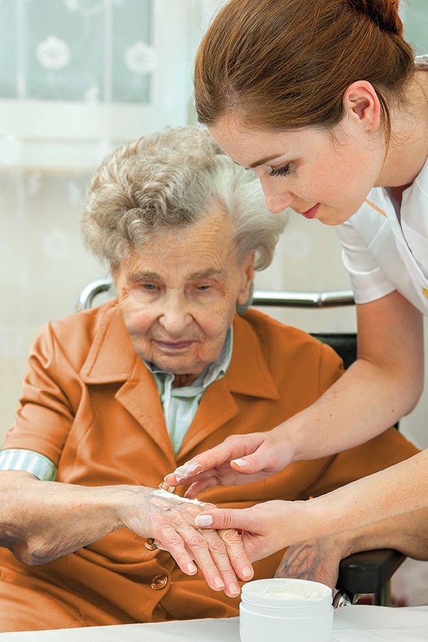 Pflegekraft versorgt ältere Dame